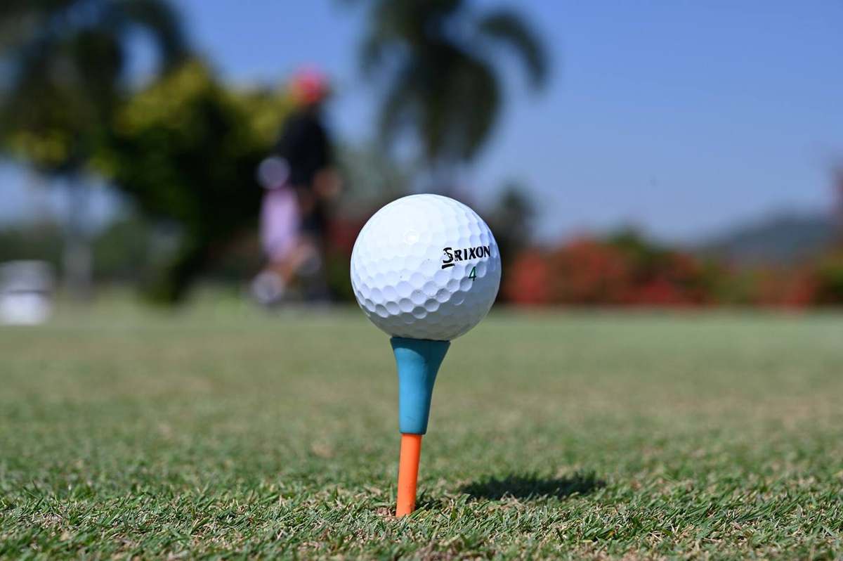 A golf ball perched on a colorful tee ready for the next drive on a sunny course